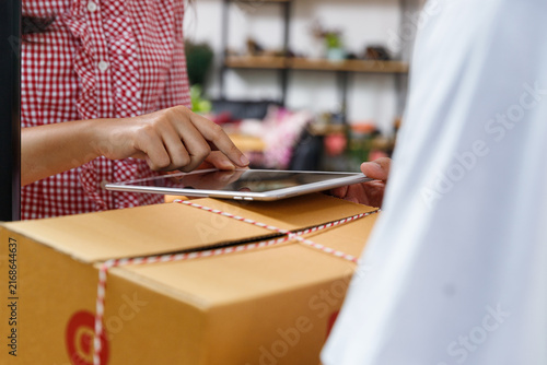 Close up of customer finger signing electronic signature on digital tablet to confirm receiving parcel from courier. Smart delivery and express logistic service concept.