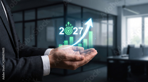 Businessman holding virtual 2027 growth chart with upward arrow and financial target