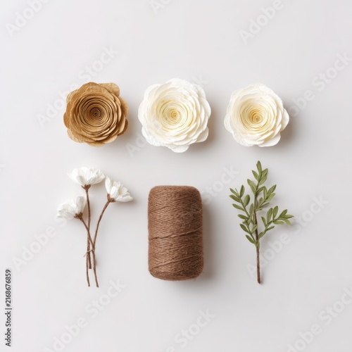 Beautiful arrangement of paper flowers with natural elements and twine on a light background for creative projects