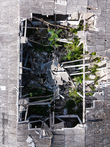Aerial view of a ruined building with a collapsed roof and debris scattered inside, overgrown with vegetation in Kulciems, Talsi Municipality, Latvia.
