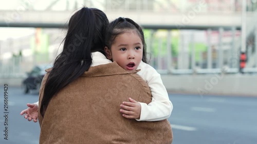 mother embracing daughter outdoors on the city street