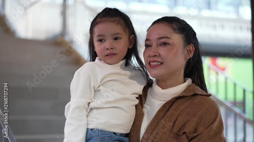 happy mother holding child girl sightseeing on footbridge in the city