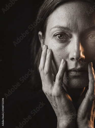 Woman covering face with both hands in dramatic monochrome portrait, emotional close-up study