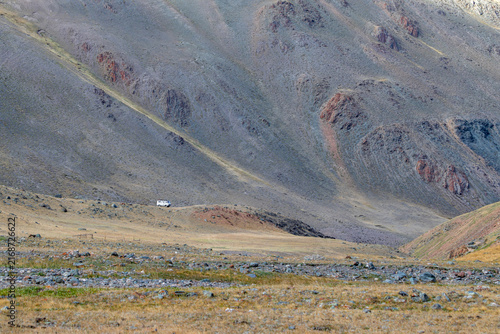 Fotografie Classic UAZ van off-road driving on a mountain slope of Sailughem range, Altai M