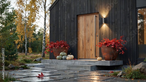 Modern rustic home exterior with wooden door and fall decorations including pumpkins and red leaves