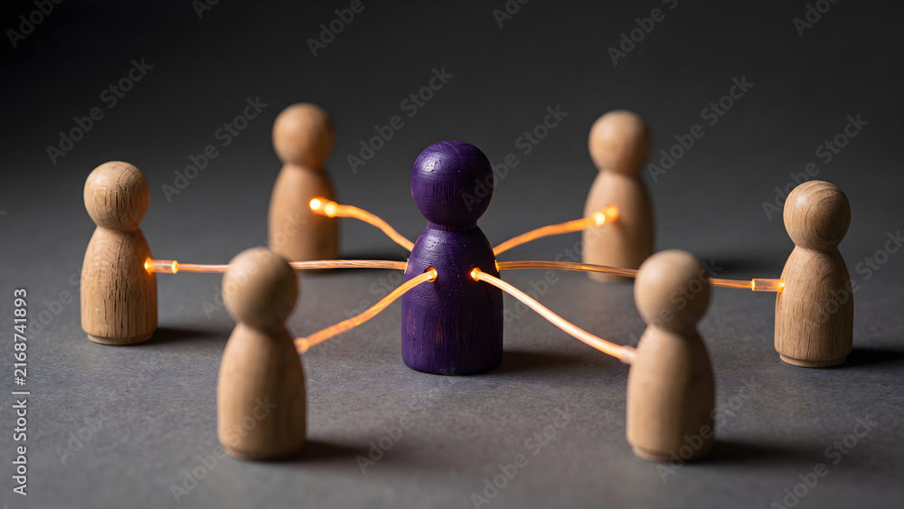 Obraz premium Purple leadership figure connected to a team of wooden dolls with glowing fiber optic cables representing network communication and teamwork