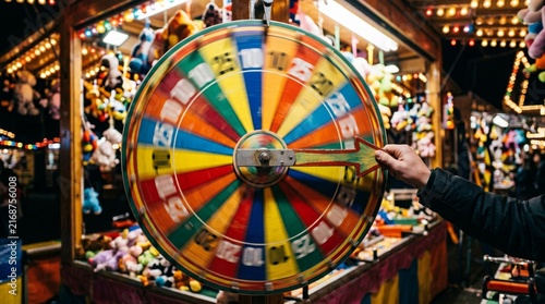 Colorful carnival prize wheel being spun by a person at a night fair.