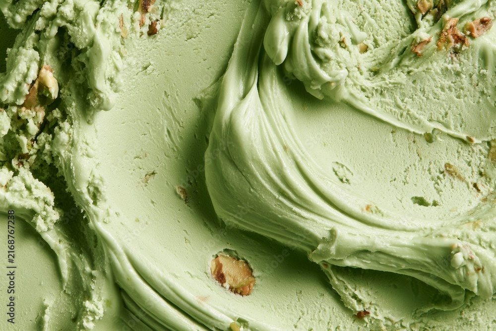 Obraz premium Mint green ice cream with nuts swirled in a container