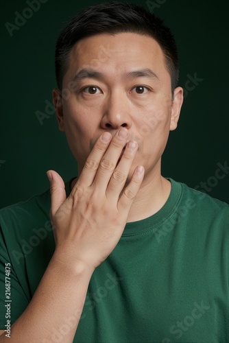 Surprised Asian Man with Hand Over Mouth Expressing Silence or Shock