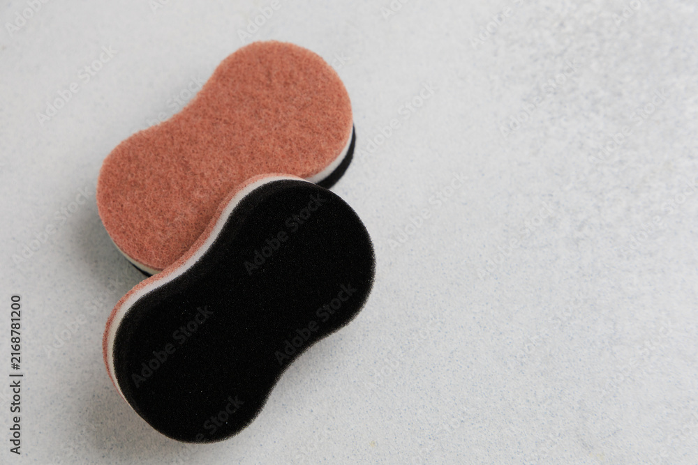 Fototapeta premium Different colored cleaning sponges placed on a light gray surface in a home setting