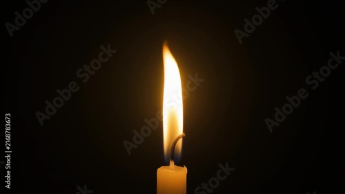 Candle-like flame rising in total darkness golden glow