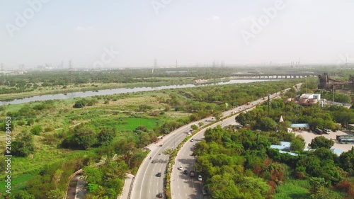 Aerial view of expressway road in New Delhi, India with lush green landscape and river.