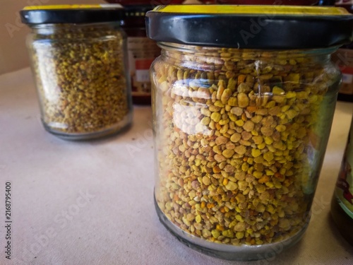 Glass jars filled with golden bee pollen granules for healthy natural nutrition.