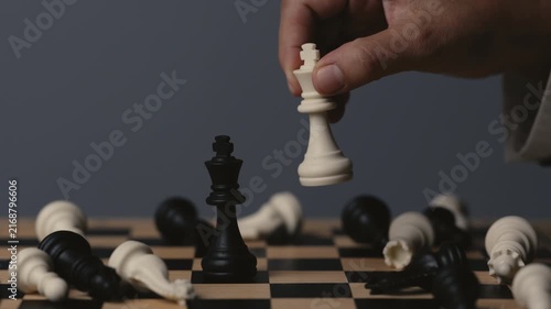 business hand holding a white chess king taking black king, checkmate concept