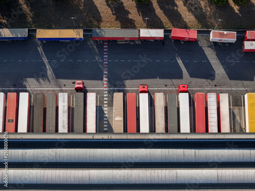 Aerial view of a logistics warehouse and freight forwarding facility with rows of colorful semi-truck trailers parked in loading bays at Settimo Torinese, Piedmont, Italy.