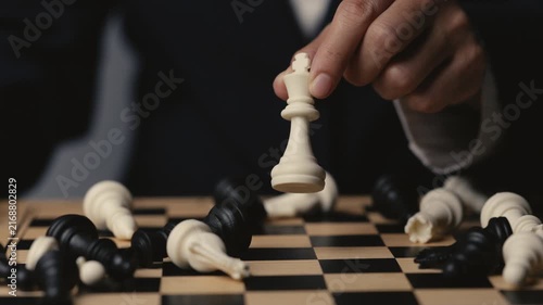 business hand holding a white chess king taking black king, checkmate concept
