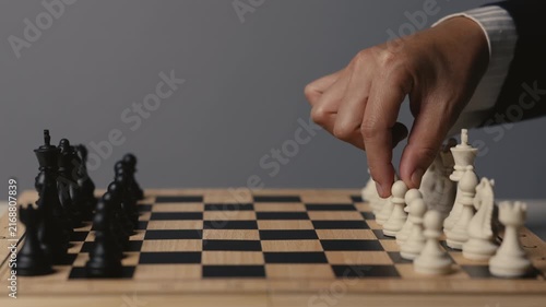 business hand moving a white pawn on a wooden chessboard, strategy