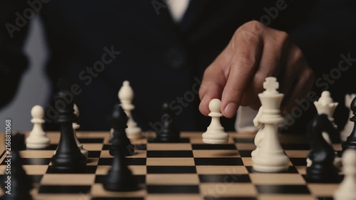 business hand moving a white pawn on a wooden chessboard, strategy