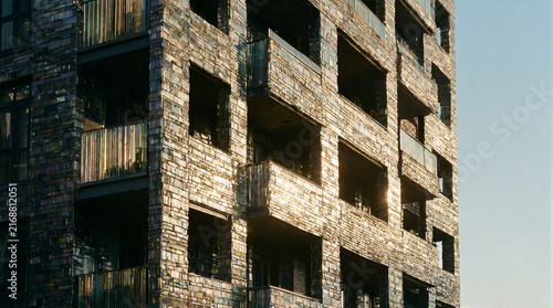 Sunlight catching shimmering translucent recycled glass bricks on a modern residential high rise facade with balconies