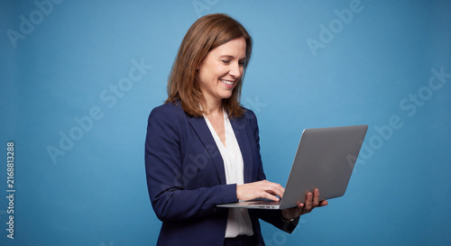 Businesswoman using a laptop computer isolated on blue background