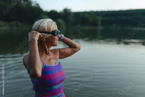 Plakat Active senior woman swimming in natural lake during indian summer.