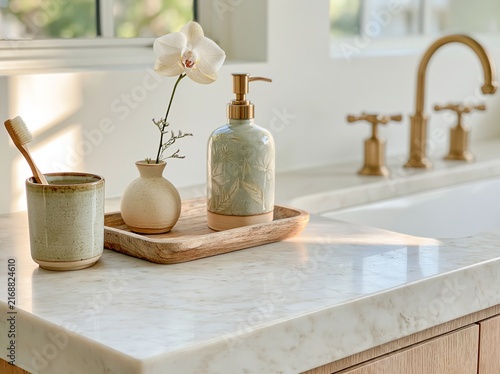 Bathroom vanity with decorative elements including a ceramic soap dispenser, a small vase with a flower, and a toothbrush holder on a marble countertop