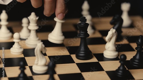 business hand holding a white chess king taking black king, checkmate concept