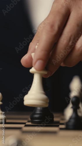business hand holding a white chess king taking black king, checkmate concept