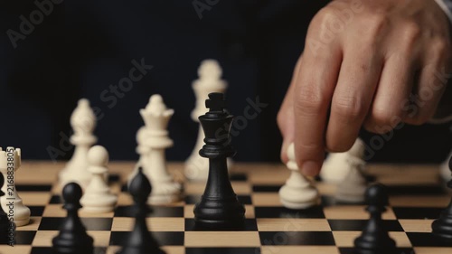 business hand holding a white chess pawn taking black king, checkmate concept