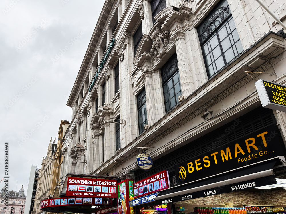 Obraz premium Busy souvenir and convenience shopping Coventry street in London, UK with crowds outside Bestmart and souvenirs megastore