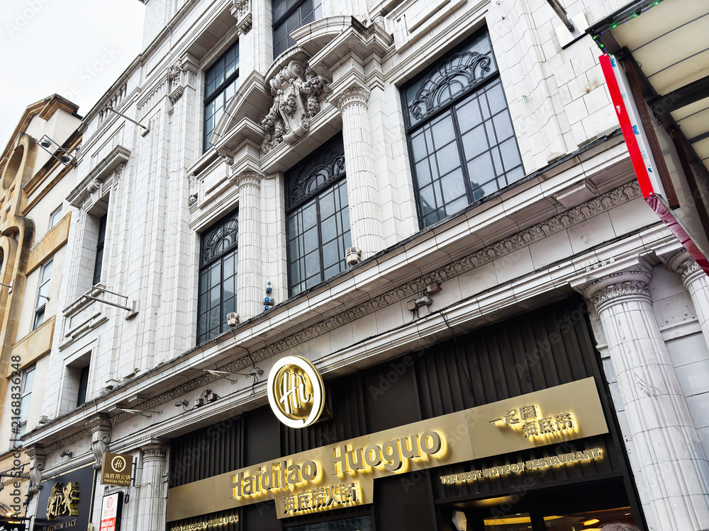 Obraz premium Busy London street scene with Haidilao Huoguo restaurant frontage and shoppers outside a historic white tiled building in London, UK