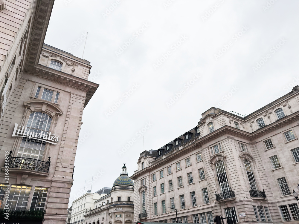 Obraz premium Historic neoclassical buildings and quiet Regent plaza under a cloudy sky in central London, UK showcasing ornate facades and large windows