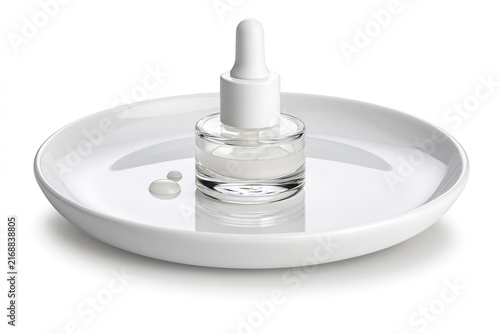 Glass dropper bottle with white pipette on a white plate, with two small drops of liquid beside it.