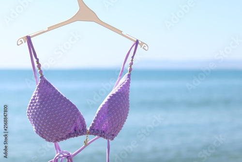 Fotografía A hanger holds a swimsuit against the background of a bright sunny beach and blue water