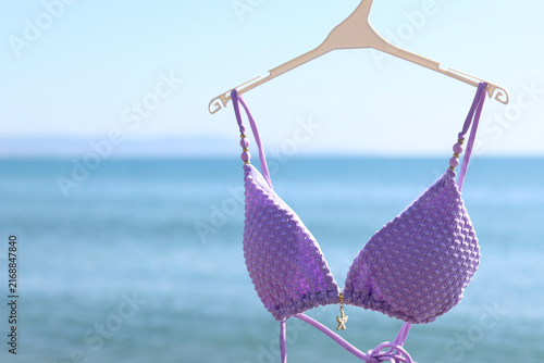 Fotografía Lilac swimsuit-bodice on a hanger against the background of the blurred sea