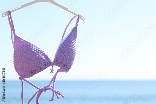 Cuadro en lienzo Lilac swimsuit-bodice on a hanger against the background of the blurred sea