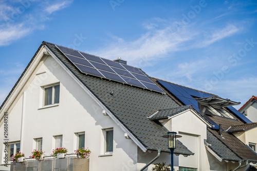 Modern residential house with solar panels installed on the roof under a blue sky