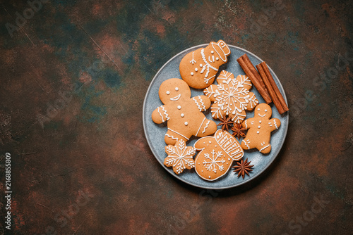 Collection of Christmas gingerbread cookies in a plate on a dark rustic background, top view, flat lay, copy space.