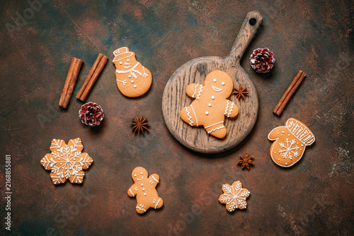 Various gingerbread cookies with cinnamon sticks and star anise on dark brown grunge background, top view, flat lay, Christmas.
