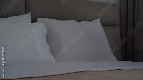 Woman arranging pillows on a bed in a cozy bedroom, home comfort and relaxing morning routine