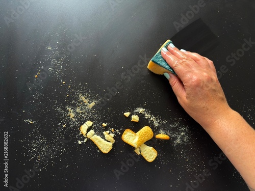 Принти на полотні Hand wiping food crumbs off black table using sponge