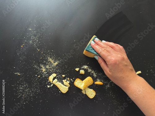 Canvastavla Hand wiping food crumbs off black table using sponge