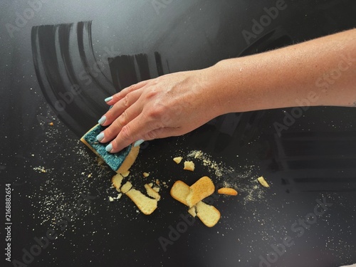 Canvastavla Hand wiping food crumbs off black table using sponge