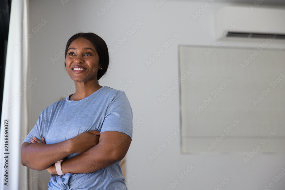 Fototapeta premium Adult African American woman posing arms crossed smiling at home by drape wearing band, copy space