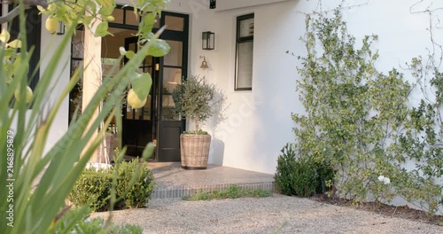 Camera is panning entrance while sun is lowering and lighting woven planter; breeze is nudging door