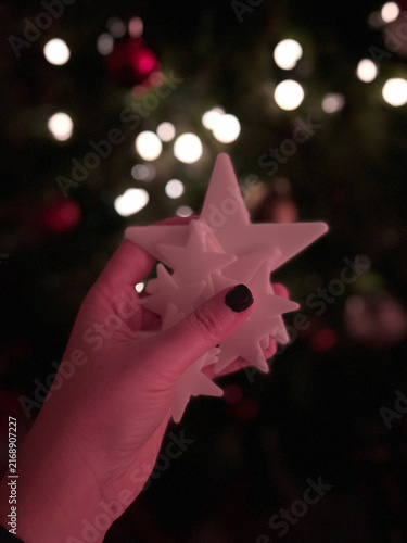 Mano sosteniendo estrella brillante frente a luces de Navidad