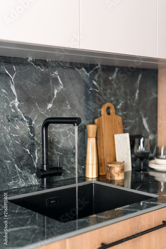 Modern kitchen interior with black faucet and green marble countertop