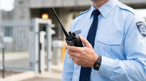 Professional security guard holding a walkie-talkie while on duty.