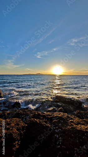 Sunset over rocky ocean coast with waves