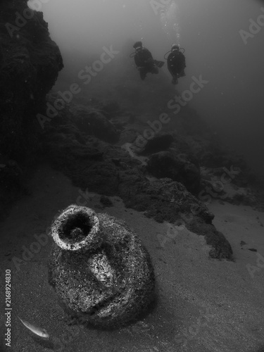 scuba divers are exploring antic old amphoras underwater